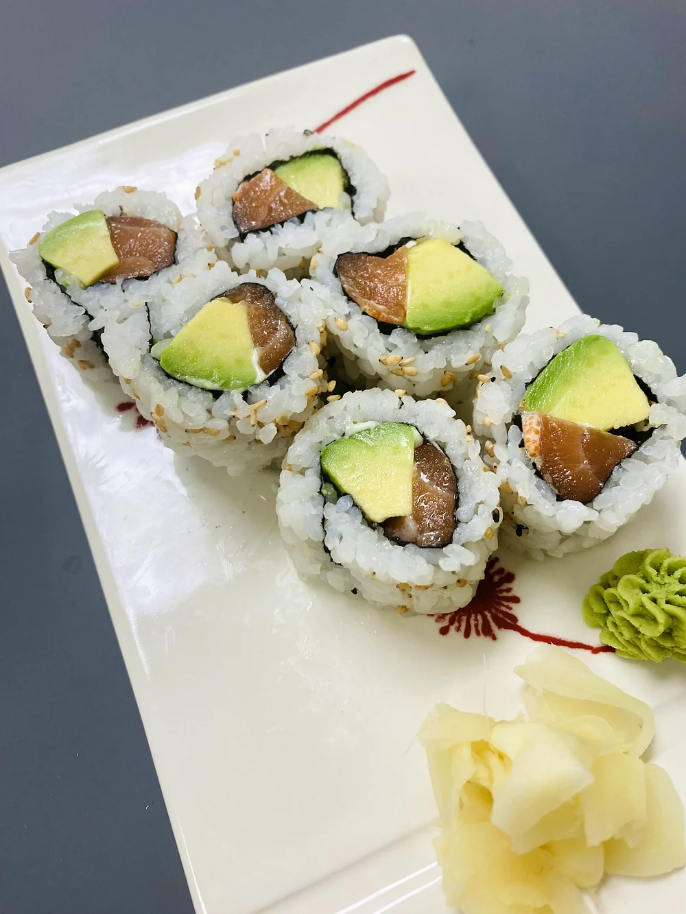 Alaska roll pieces with salmon and avocado on a white plate with pickled ginger and wasabi at Hana Sushi, Winnipeg